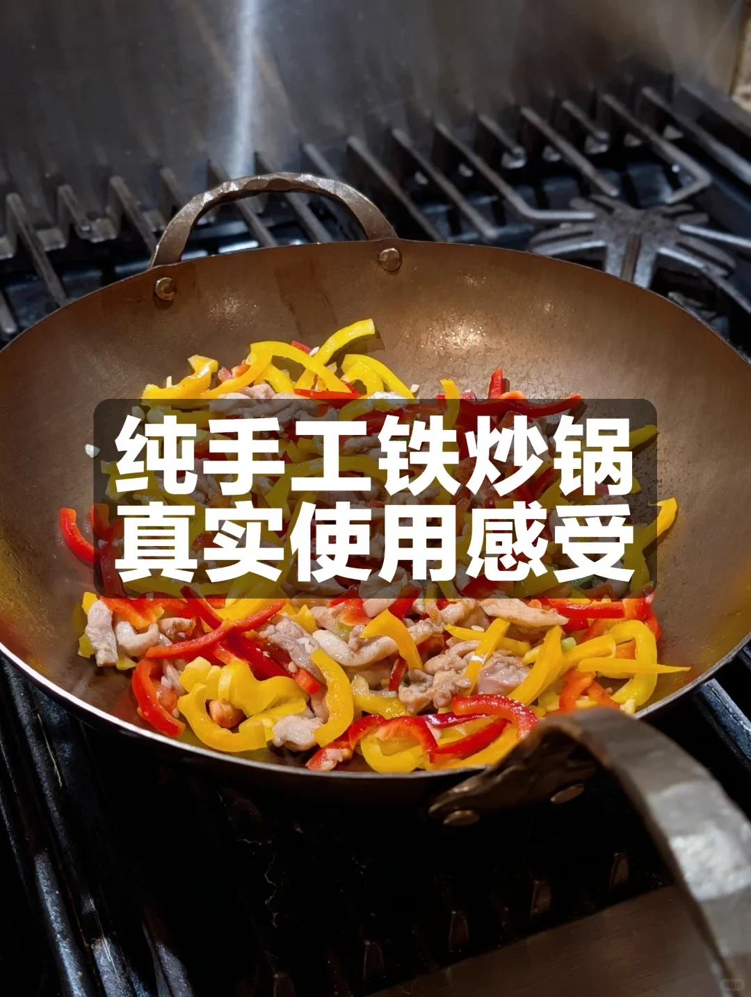A hand-forged carbon-steel wok on a gas stove holds stir-fried meat with red and yellow pepper strips. A Chinese title overlay describes a handmade steel wok and real-world use impressions.