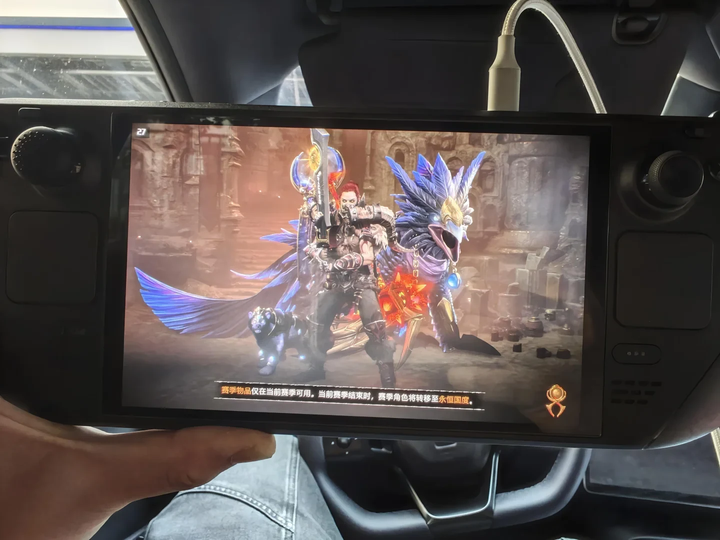 A Steam Deck handheld console running a fantasy role-playing game on a loading screen, featuring an armored character holding a sword alongside a glowing feline companion and a feathered mount.
