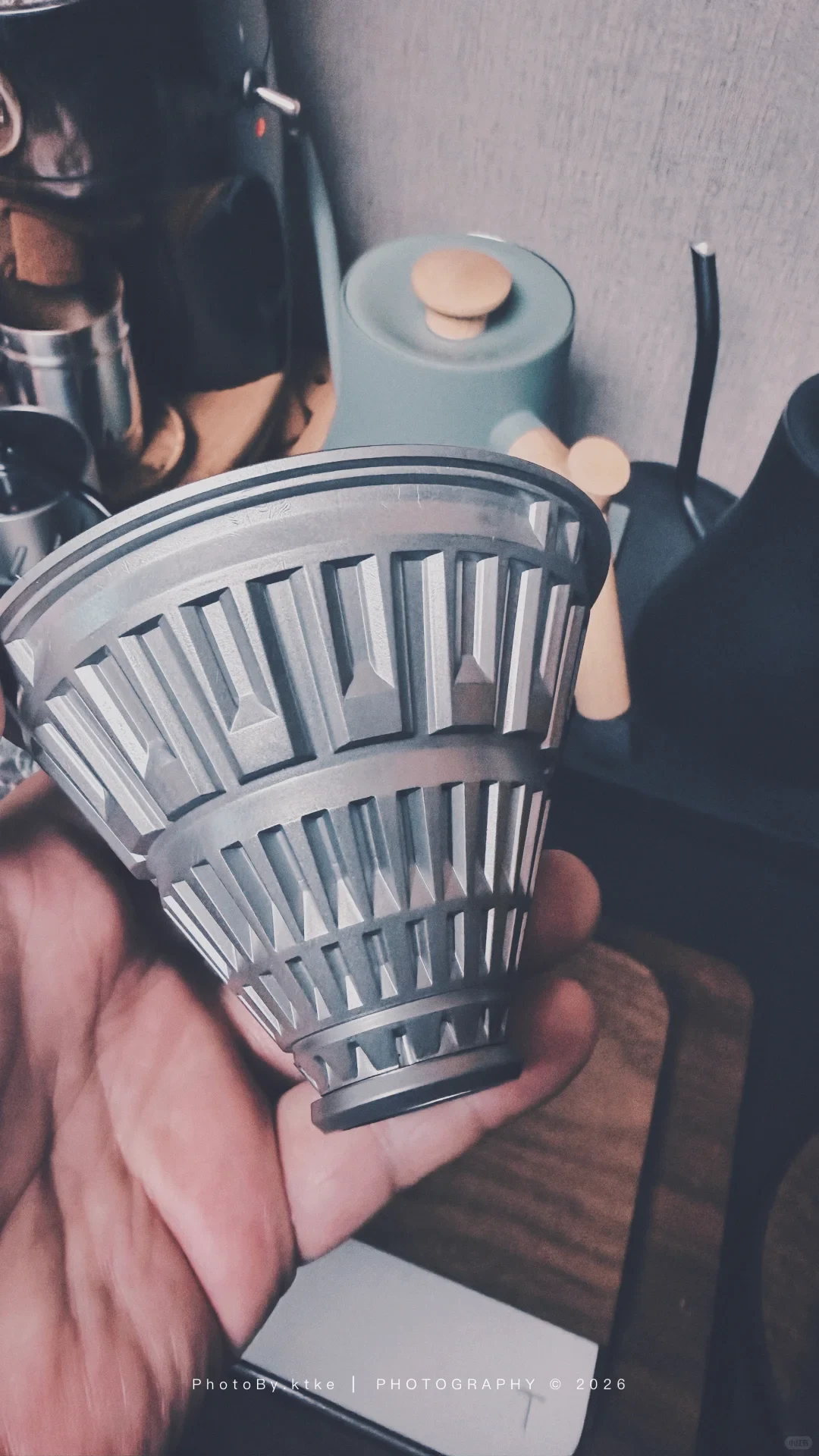 The owner holds the exposed metal core of a TIMEMORE Crystal Eye VECTOR coffee dripper with its black sleeve removed.