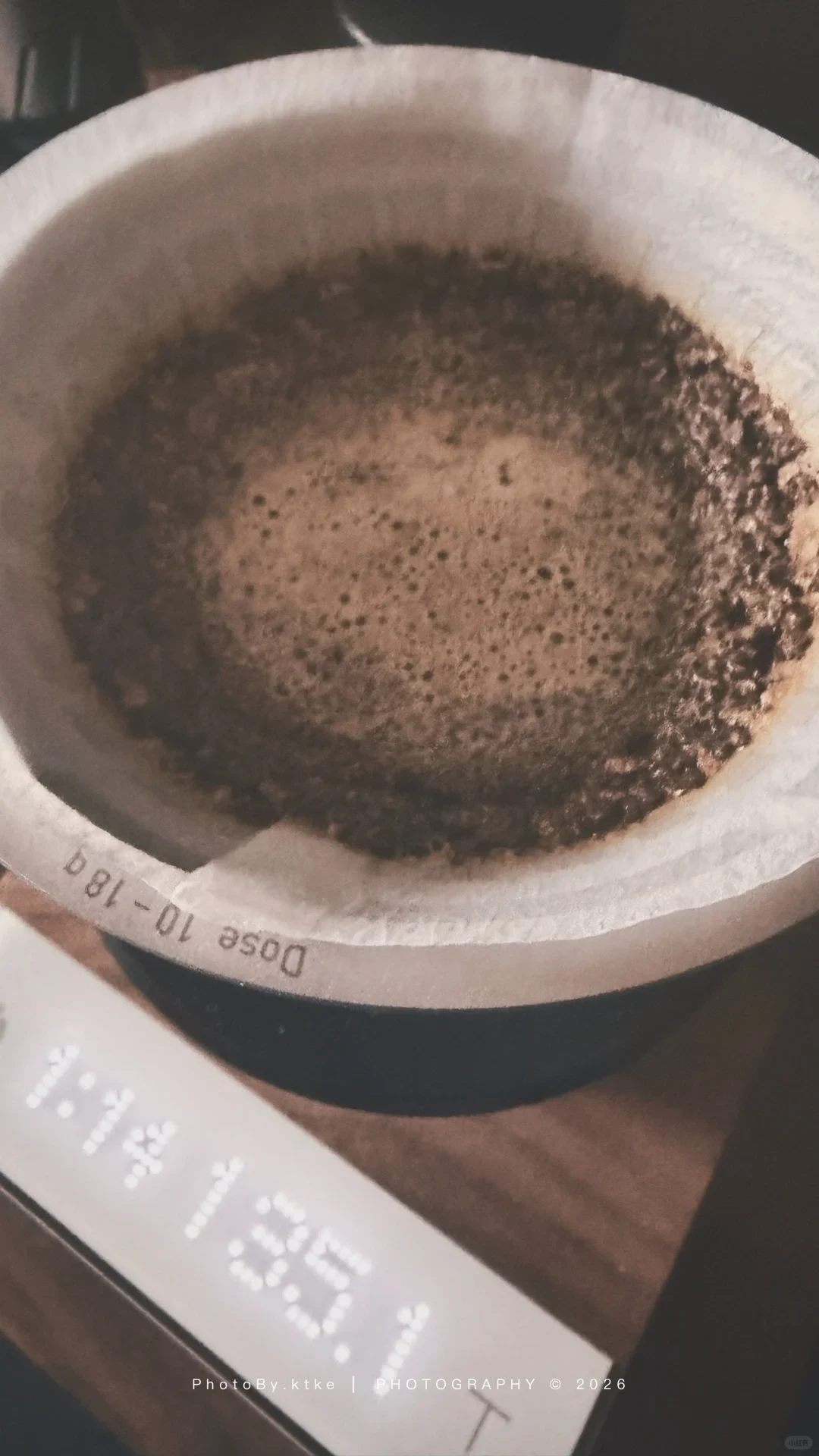 Coffee slurry sits in a paper filter inside the VECTOR dripper over a scale; the rim is marked for a 10–18 g dose.
