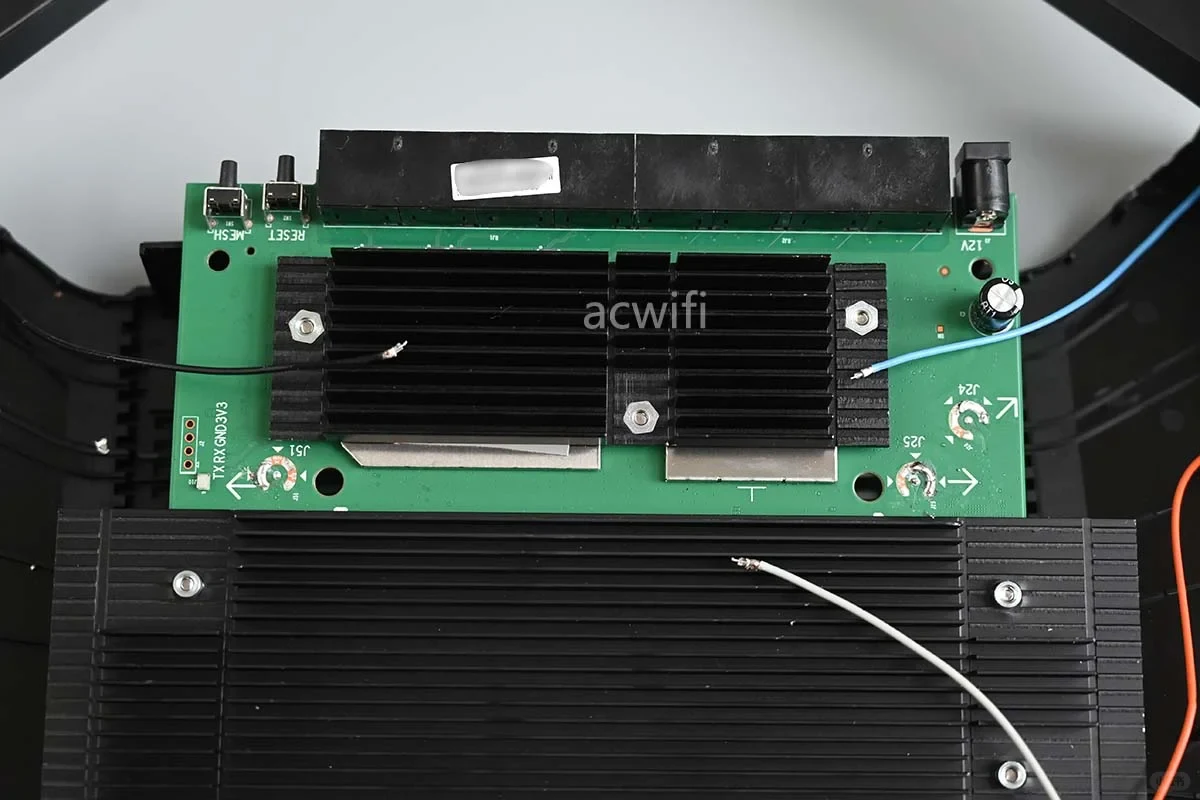 Internal teardown view of the TP-LINK 7DR7290 router showing a green printed circuit board with black finned heatsinks, Ethernet port housings, disconnected antenna leads, and onboard buttons.