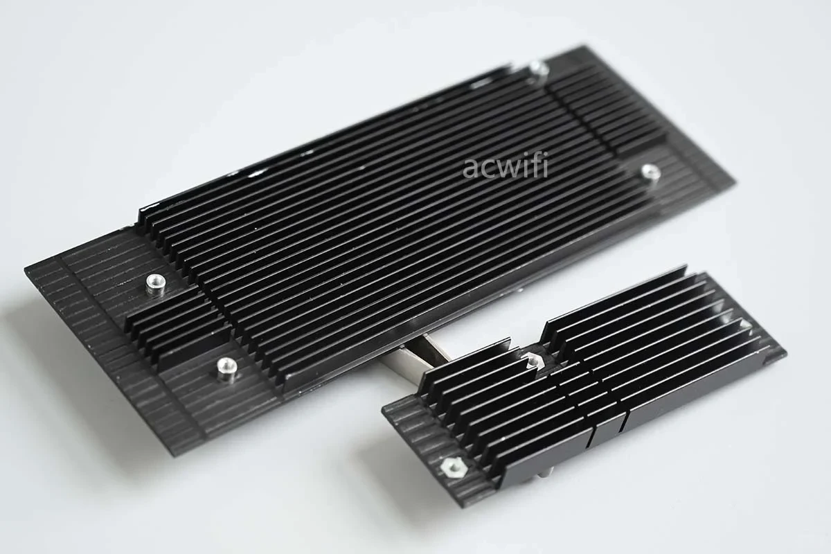 Two black finned aluminum heatsinks of different sizes from the router teardown resting on a flat white surface.