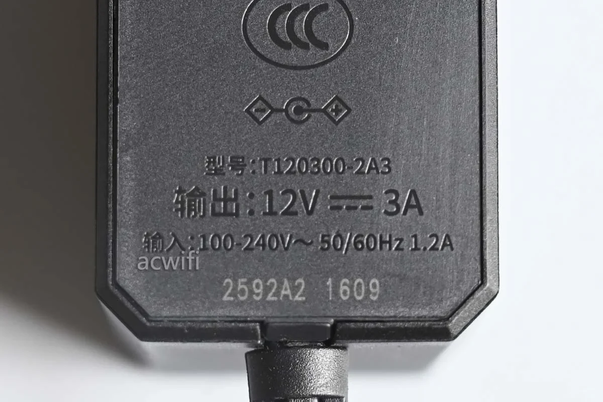 Close-up view of the power adapter label for the TP-LINK 7DR7290 router, showing model number T120300-2A3, input specifications, and output rated at 12V 3A.
