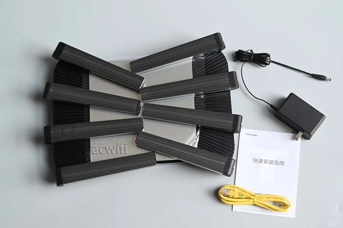 Top-down view of the TP-LINK 7DR7290 router with eight flat antennas folded over its body, laid out next to a black power adapter, a yellow Ethernet cable, and a printed quick start booklet.