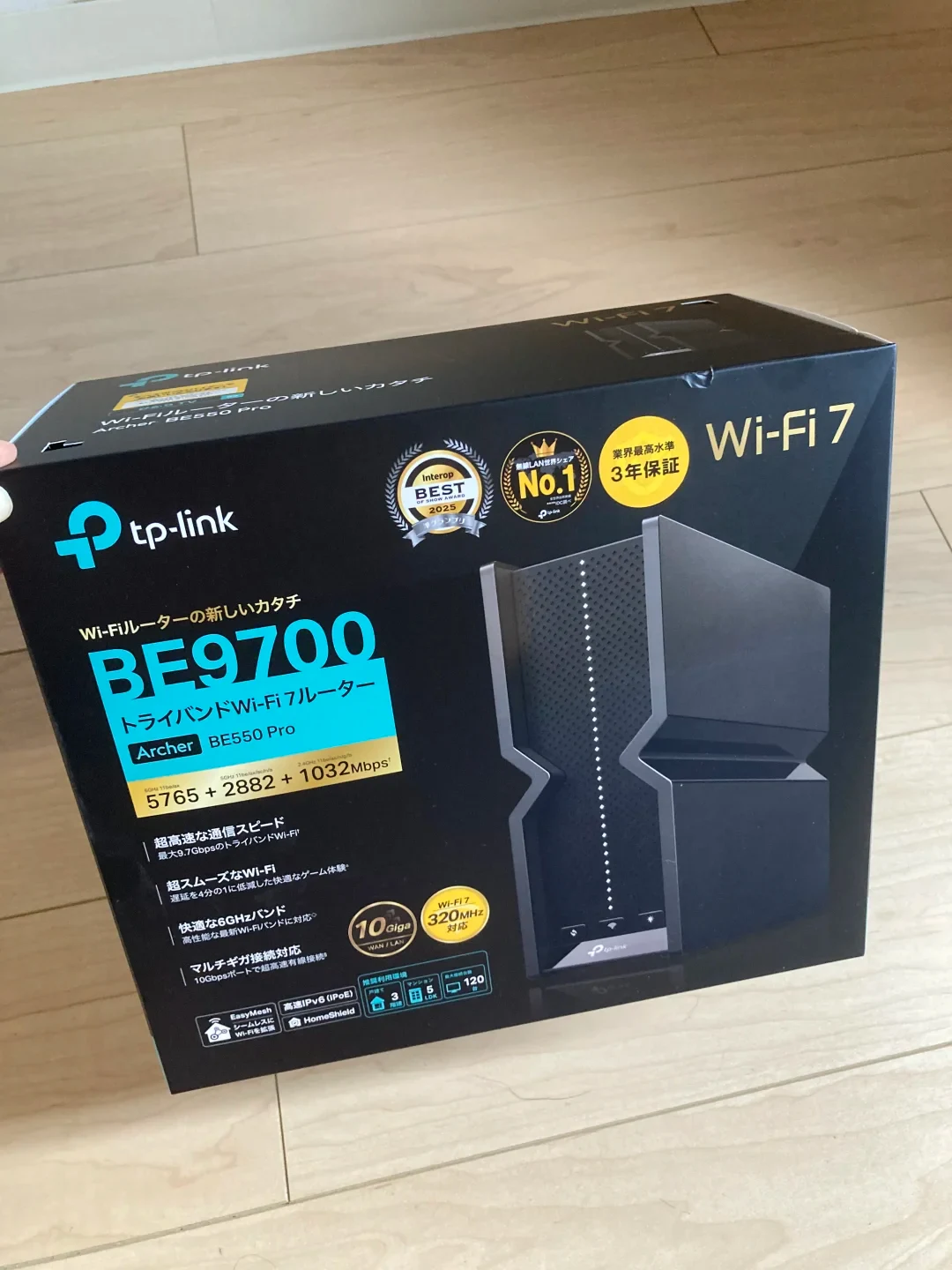 The retail packaging for a TP-Link Archer BE550 Pro BE9700 Tri-Band Wi-Fi 7 router sitting on a light-colored wooden floor.