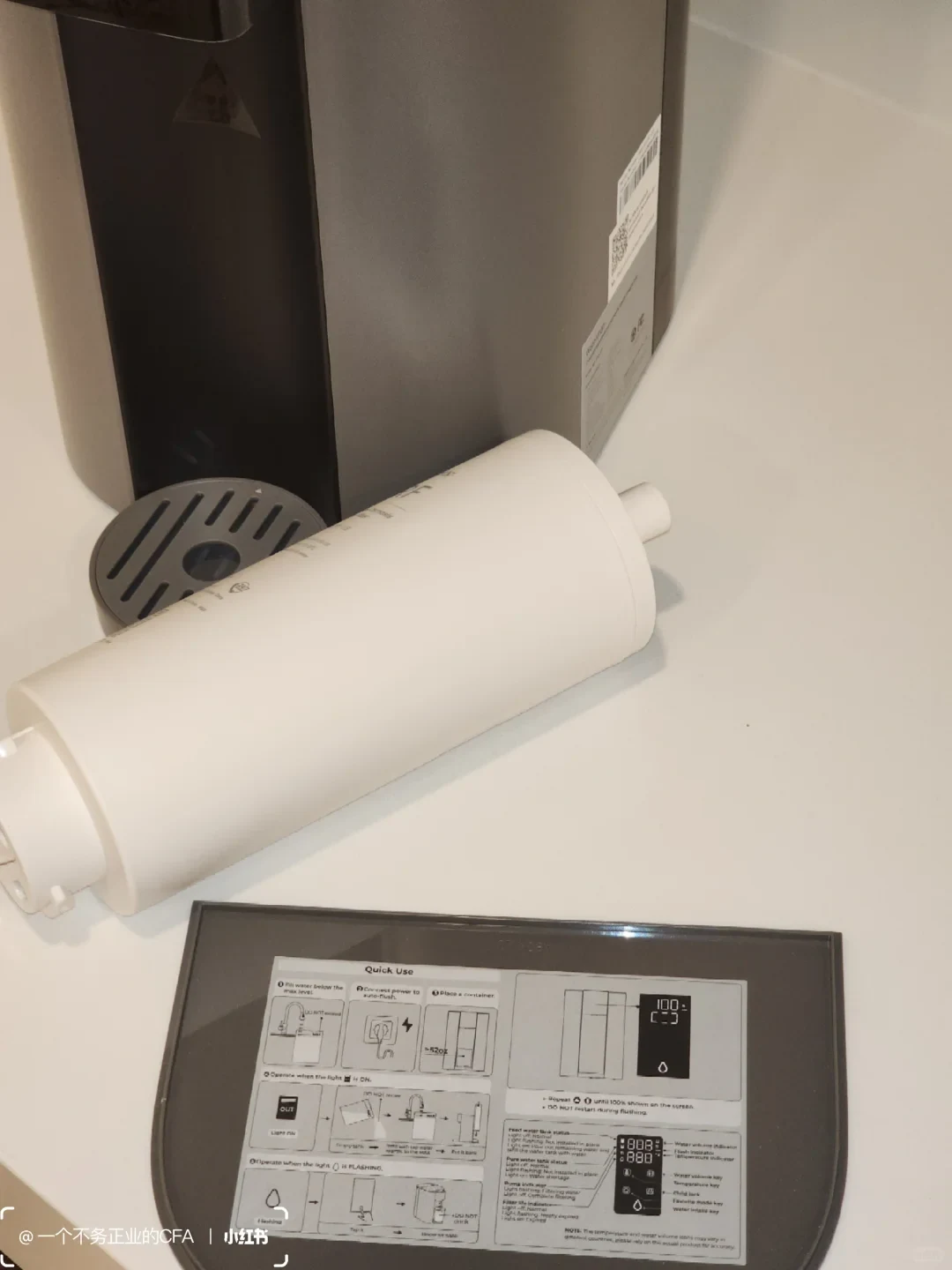 The C1H’s removed cylindrical filter lies beside the countertop dispenser. Its top cover below carries an English quick-use guide with tank-refill and flushing diagrams.