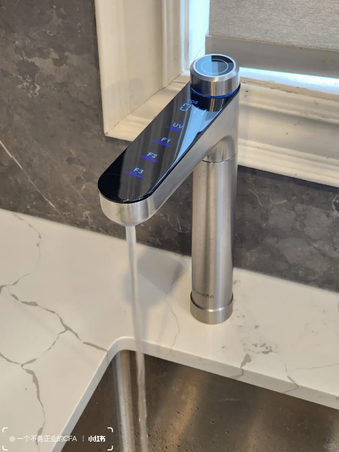 A stainless-steel faucet with a glossy black touch-control panel runs water into a sink. The panel has blue-lit labels including UV, F1, F2, and F3.