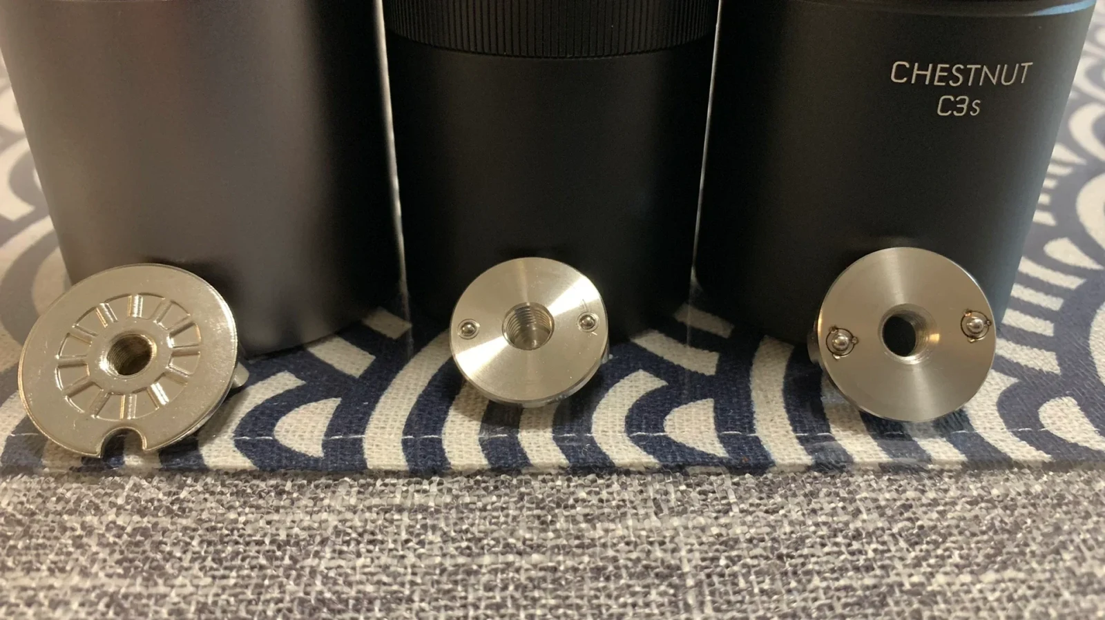 The threaded undersides of the zeroHero Z3 Pro, MAVO Wizard 2.0 espresso and TIMEMORE Chestnut C3s adjustment knobs, from left to right, are shown in front of the corresponding grinder bodies.