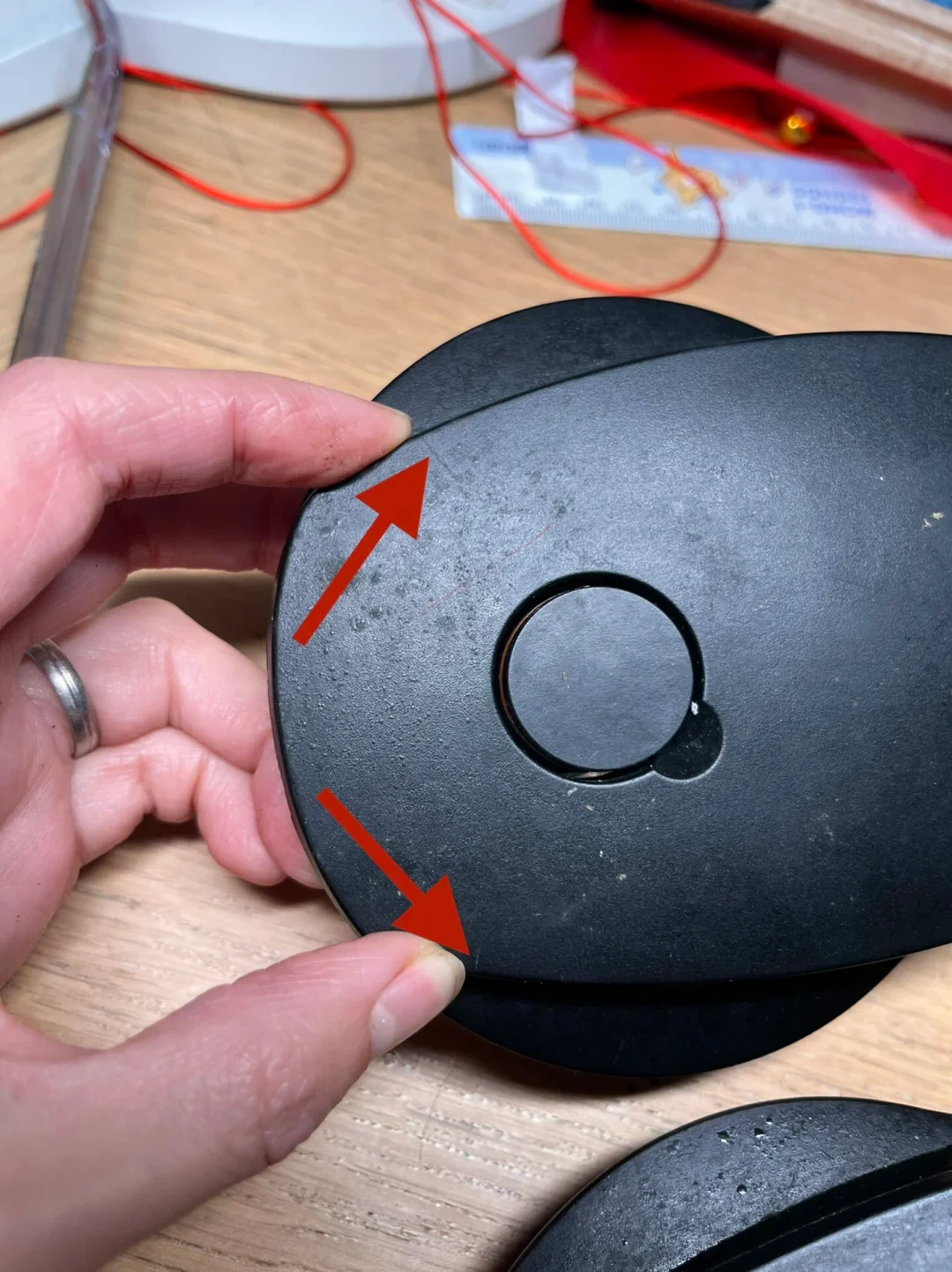 Close-up of a WMF pressure-cooker lid handle housing, with two red arrows marking cracks in the black plastic.