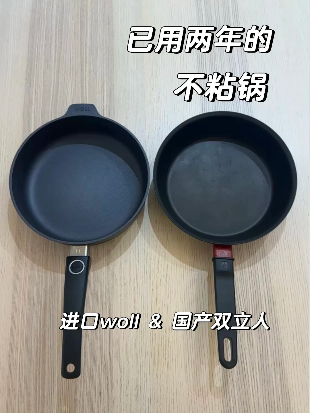 Two black non-stick frying pans placed side by side on a light wooden surface, with a Woll pan on the left and a Zwilling pan on the right.